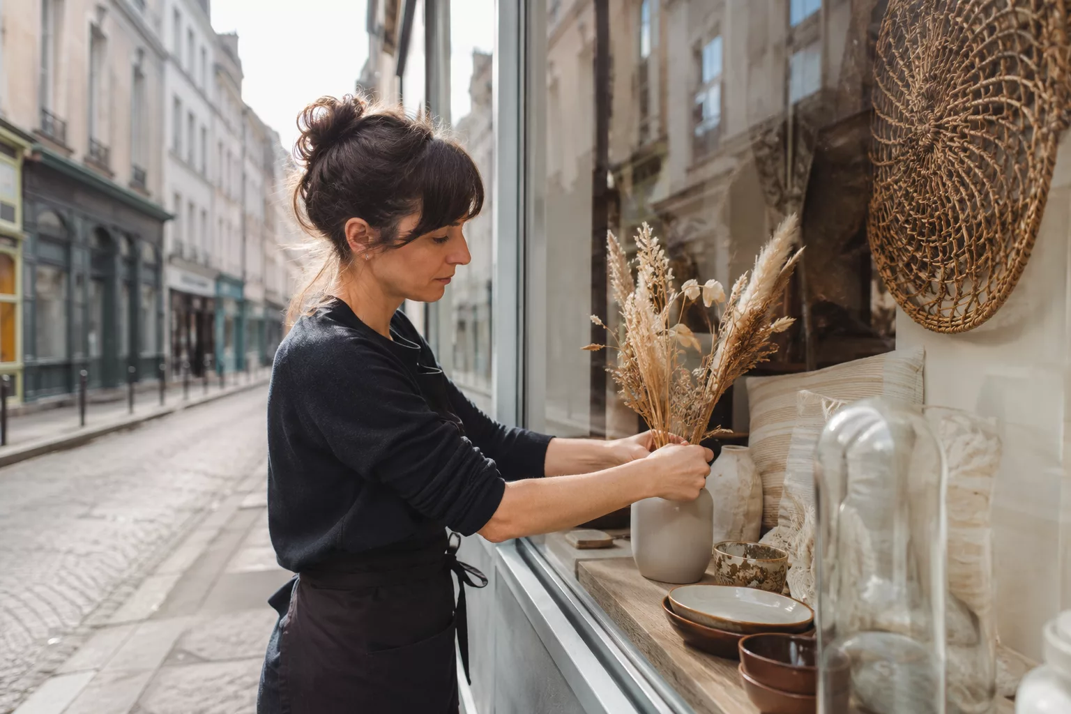 Commerçante réorganisant la vitrine de sa boutique en début de journée