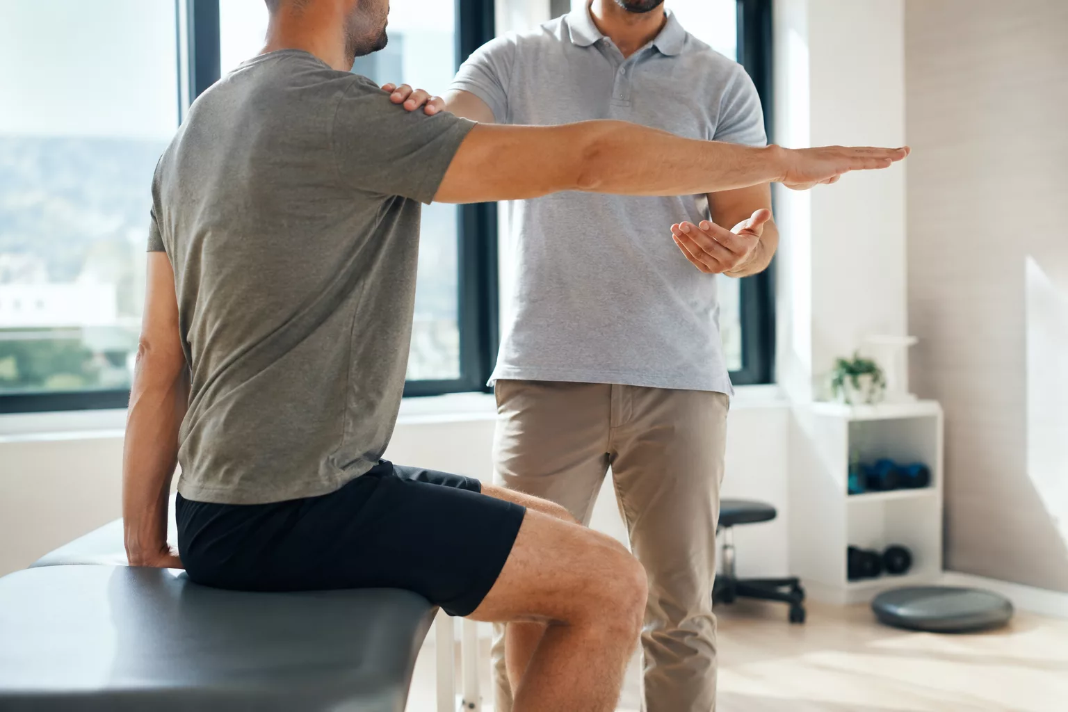 Praticien expliquant un exercice à un patient dans un cabinet de kinésithérapie